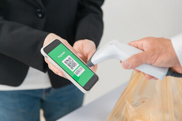 コンビニでスマートフォンを使ってQRコード決済する女性

