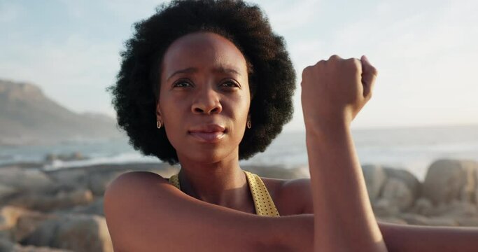 Fitness black woman, focus mindset and stretching arms for running workout, training and exercise at beach outdoors. Face of thinking runner, strong athlete and healthy african person with motivation