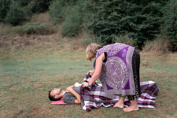 Barefooted female covering man with blanket during shamanic healing procedure
