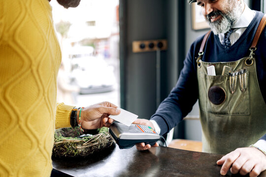 Crop client paying for haircut in barbershop