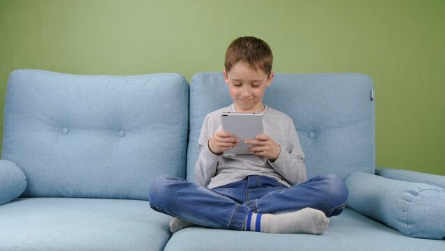 The child undergoes distance learning through online video training, the Internet, using a tablet, at home. The concept of home remote learning. Kid doing homework at home