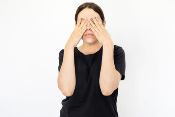 Portrait of young tired woman in black T-shirt covering eyes. Female model with plain face bored or...