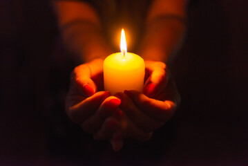 Candle in female hands on black dark background.Prayers candle in hands.