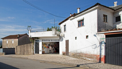 Maison blanche avec son atelier garage de réparation dans un quartier pauvre d'une ville du Portugal en été.