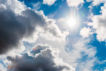 Heavy dark storm raining clouds over the blue sunny sky.