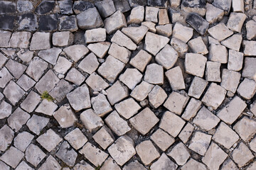 Trottoir pavé dans un état de délabrement où les cubes de pierre sont disjoints. Rue d'une ville aux maisons en ruine.