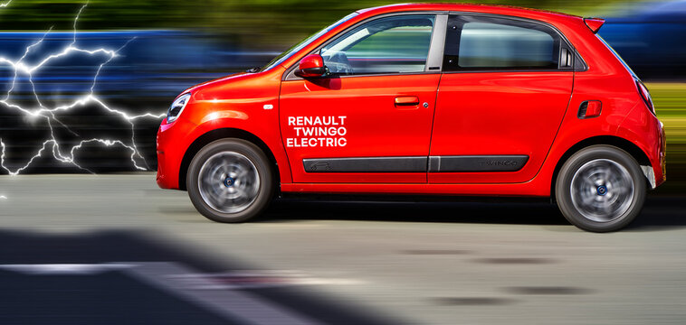 Renault Twingo electric, side view of red electric small car against dynamic blurred background with flashes from front, vehicle location Hannover, Germany, September 17, 2022