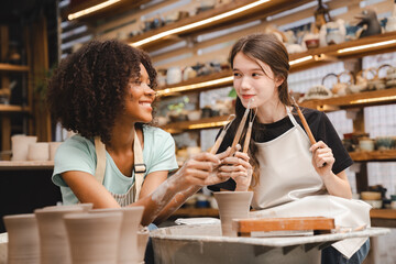 Creative afro American young woman artist molding clay on pottery wheel, Workshop in ceramic studio, clay making of a ceramic pot on the pottery wheel, hobby and leisure with pleasure concept