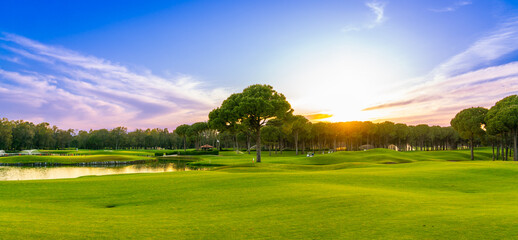 Panorama of dawn over a golf course with a pine forest in the background in Belek Turkey - obrazy, fototapety, plakaty