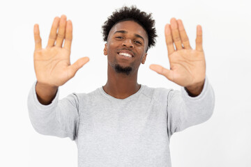Portrait of happy African American man making stop gesture. Young bearded guy wearing white sweater...