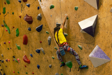 little girl climbing a rock wall indoor