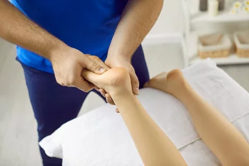 Printed roller blinds Massage parlor Woman getting treatment in health spa. Male masseur with hands makes acupressure on legs of young woman in modern massage parlor. Close up of male hands massaging woman's legs lying on massage table.