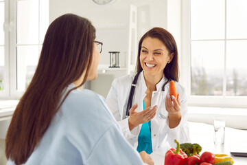 Doctor giving patient consultation on good nutrition habits. Happy dietitian or nutritionist helping woman with diet plan and weight loss, sharing wellness advice, explaining which foods are healthy