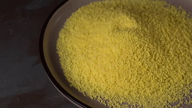 Couscous sprinkled with a wooden scoop. Dry ingredient for cooking side dish or salad