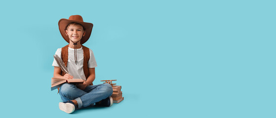 Cute little cowboy with books on light blue background with space for text