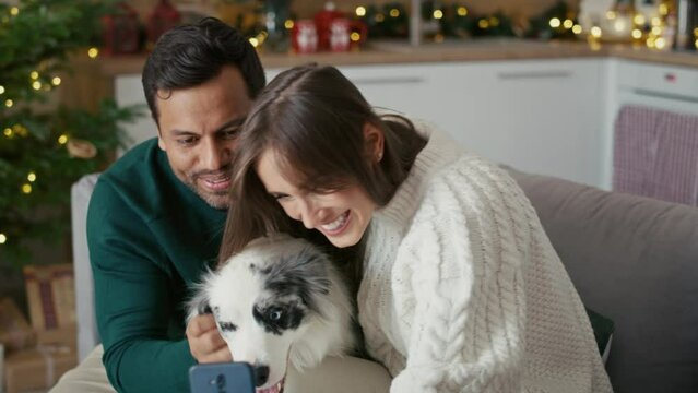 Happy multi ethnicity couple taking selfie with dog during the Christmas. Shot with RED helium camera in 8K. 