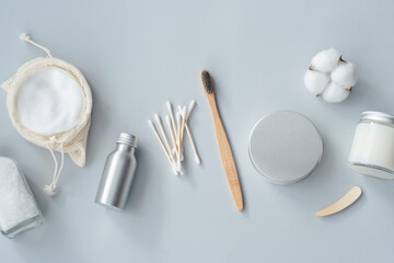 Zero waste concept. Metallic bottle and can, reusable cotton rounds. Packaging for cleaning teeth without plastic. Wooden toothbrush and glass jar with toothpaste on a grey background. Bathroom