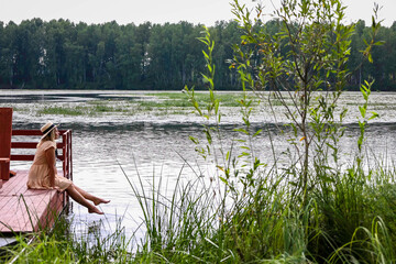 girl sitting on the pier with her feet in the water