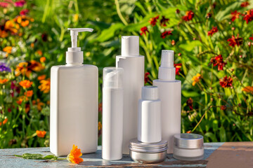 Set of cosmetic for skin care face, body on bright floral background. White blank cosmetics bottles, jar and stones. Natural Organic Spa Cosmetic Beauty Concept Mockup Front view