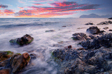 Dramatic landscape with sea shore, waves and stones on the stones beach.
