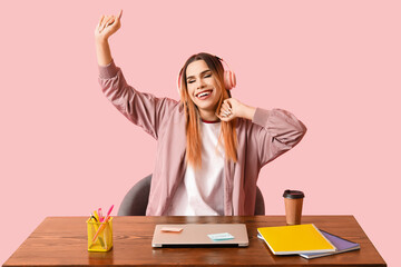 Transgender programmer with laptop at table on pink background