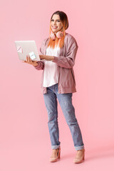 Transgender programmer with laptop on pink background