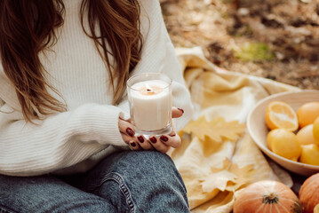 Girl holding burning candle in hands. Having a good time outdoor in autumn forest, burning aromatic...