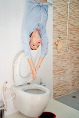 Woman playfully diving into the toilet. Household concept.