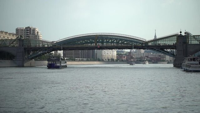 Metal and glass bridge or river. Russia, Moscow. 25 juli 2022. River tram sails along the Moskva River with passengers, river walk on a closed boat. High quality 4k footage
