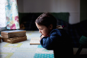 Fototapeta Mała dziewczynka odrabia lekcje i uczy się czytać obraz