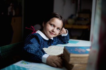 Mała dziewczynka odrabia lekcje i uczy się czytać - obrazy, fototapety, plakaty