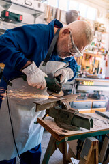 A man welder with safety glasses polishes the metal angle grinder in a workshop