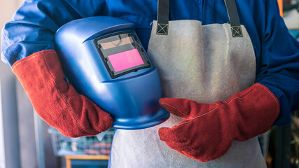 A man welder with safety helmet working with arc welding machine in the workshop