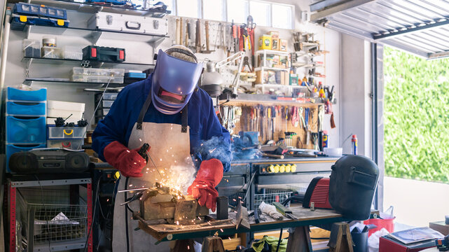 Metal processing with a man using welding machine for steel seam. Special clothe
