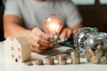 Businessman using calculator to calculate and holding a light bulb and Stacking coins, piggy,...
