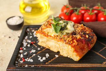 Wooden board of tasty Italian pie with mozzarella and pesto sauce on table, closeup