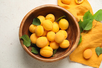 Bowl of ripe apricots on light background