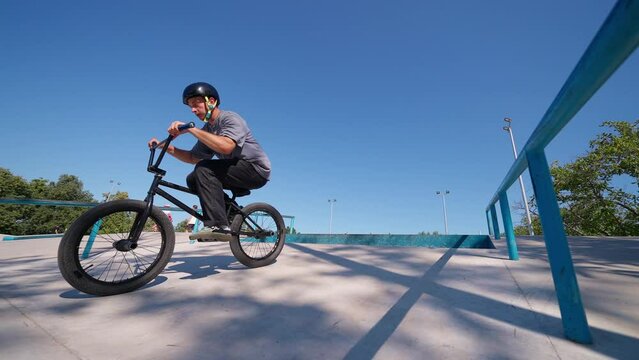 A professional cyclist rides and performs tricks on bmx. Beautiful stunts dand bike jumps in the park on a concrete platform with obstacles. BMX.