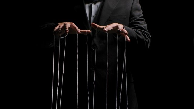 Man hands with strings on fingers on black background. Violence, harassment, bullying concept. Master in business suit, abuser using influence to control person behavior. Manipulation of government.