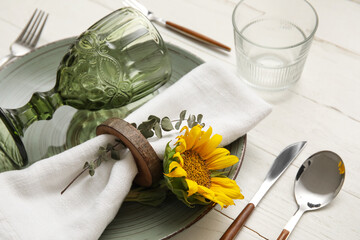 Dinnerware and sunflower on white wooden table, closeup
