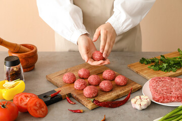 Female chef cooking meat balls at table, closeup