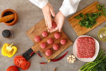 Female chef cooking meat balls on grunge background, top view