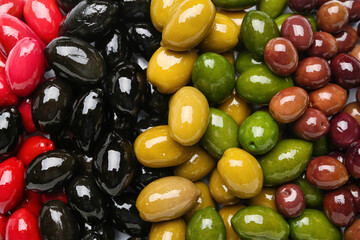 Different kinds of delicious olives as background, closeup