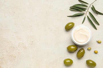 Jar of cream with green olives and plant branch on grunge background