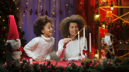 African American mom and little daughter burning white candles with wow delight emotions. Woman and...