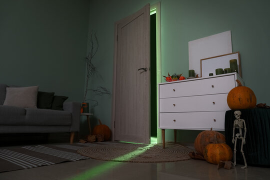 Door with glowing green light in dark living room decorated for Halloween