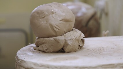 Round gray piece of clay or dough lying on table in workshop. Soft shaped ball of clay for...