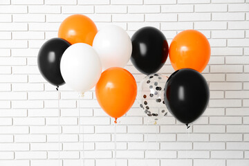 Halloween balloons near white brick wall