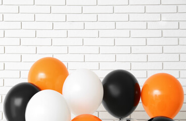 Halloween balloons near white brick wall