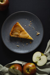 A slice of apple tart on dark plate